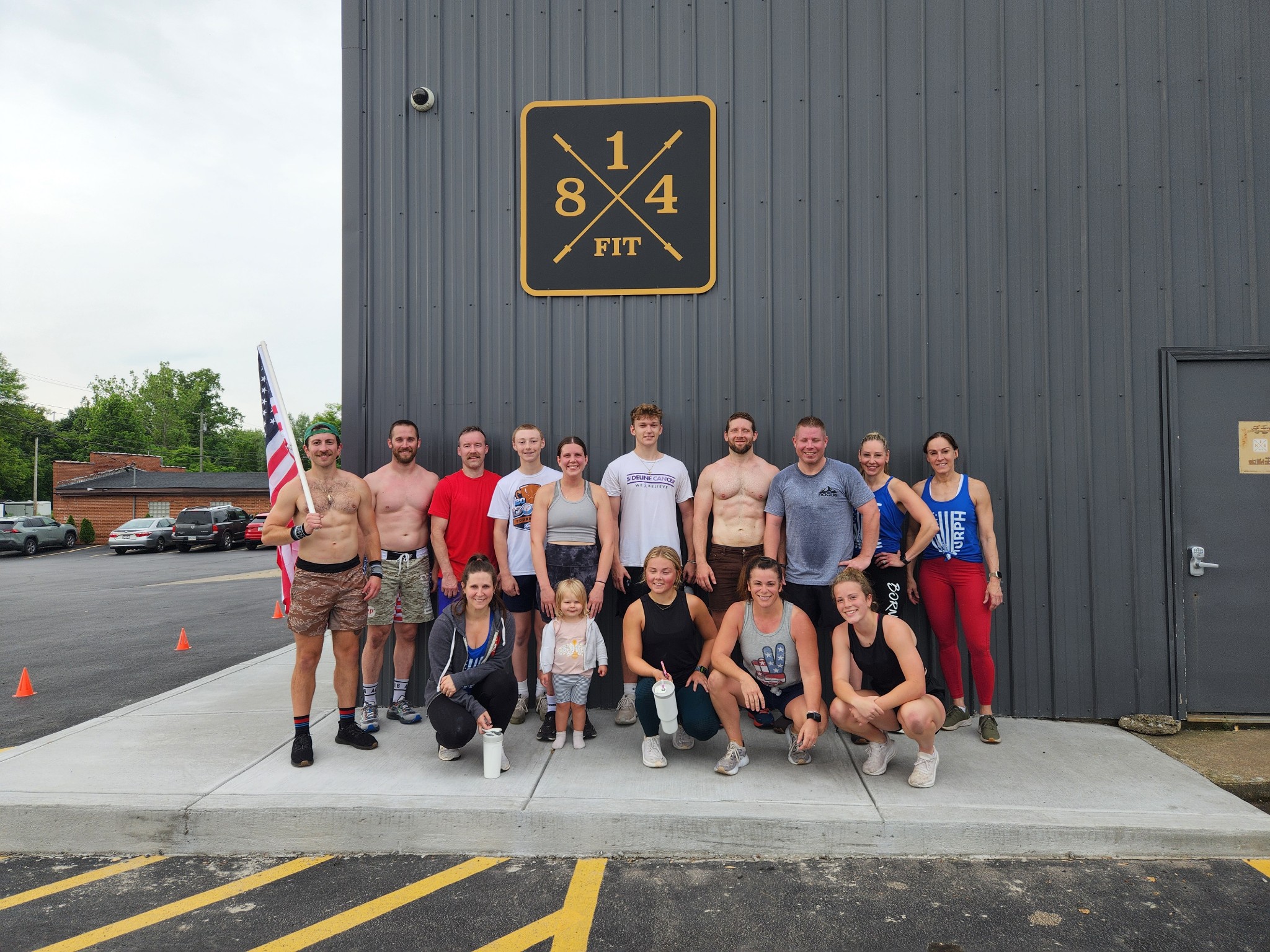 a group of athletes standing together and holding the american flag in front of the 814 facility.